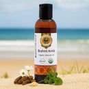 Bottle of Brahmi Amla organic ayurvedic oil with a beach background