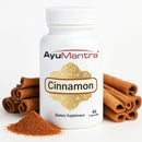 AyuMantra cinnamon dietary supplement bottle with cinnamon sticks and powder on a white background