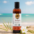 Bhlingraj organic ayurvedic oil bottle on a beach with ocean in the background