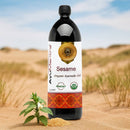 Bottle of AyuVitara Sesame Organic Ayurvedic Oil with sesame seeds and plant in sand
