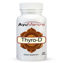 A bottle of Thyro D Tablets by AyuMantra with 60 tablets inside. The label is white with a brown decorative border and text detailing the product name and purpose as a dietary supplement.