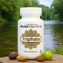 AyuMantra Triphala dietary supplement bottle with natural elements on a blurred nature background