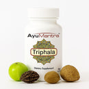 AyuMantra Triphala dietary supplement bottle with Triphala fruits on a white background