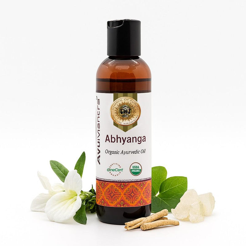 Bottle of Abhyanga organic ayurvedic oil with flowers and cinnamon sticks on a white background