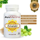 AyuMantra Amalaki tablets bottle with purity seal, organic amla fruits and herbal powder.