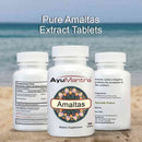 AyuMantra Amaltas supplement bottles on a beach with ocean in the background.