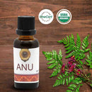 Bottle of ANU oil with organic certification logos on a wooden background