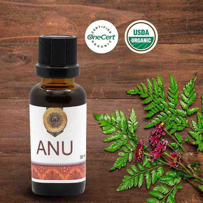 Bottle of ANU oil with organic certification logos on a wooden background