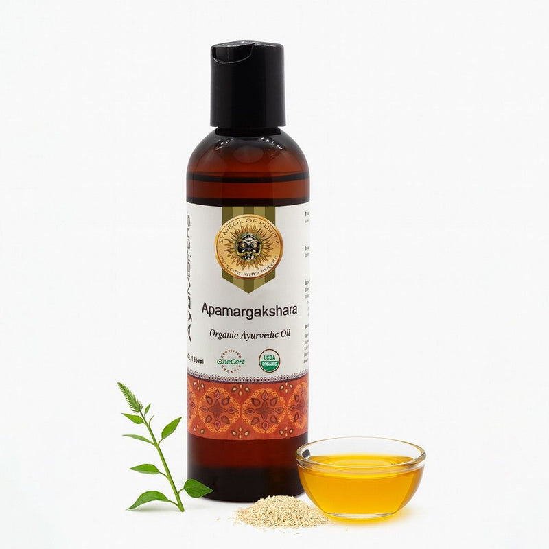 Bottle of Apamargakshara organic ayurvedic oil with a small bowl of oil and seeds on a white background