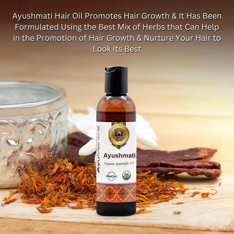 Ayushmati hair oil bottle with herbs on a wooden surface.