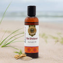 Bottle of Bal-Shatavari Ayurvedic Oil on a sandy beach with grass and sandalwood.