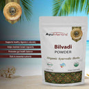 AyuMantra Bilvadi Powder packaging with product details on a scenic background