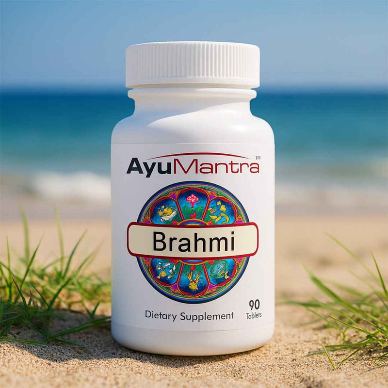 Ayumantra Brahmi tablets bottle on sandy beach with ocean in background.