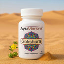 AyuMantra Gokshura dietary supplement bottle on sand with desert background.