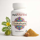 AyuMantra Gokshura dietary supplement bottle with flower and powder on a white background.