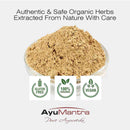 Herbal powder in a glass container with AyuMantra branding and certification logos on a white background.