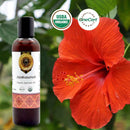 Bottle of Japakusumadi organic Ayurvedic oil next to a red flower with USDA Organic and OneCert logos.