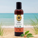 Bottle of Jatyadi Organic Ayurvedic Oil on a beach with ocean in the background
