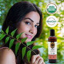 Woman holding neem leaves with a bottle of Jatyadi Organic Ayurvedic Oil and organic certification logos in the background.