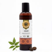 Bottle of Jatyadi organic ayurvedic oil with a leaf and seeds on a white background