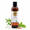Bottle of Kapha organic ayurvedic oil with leaves and coconut on a white background