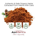 Pile of brown powder with herbs and AyuMantra branding on a white background