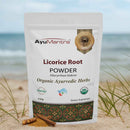 AyuMantra licorice root (yastimadhu) powder pouch with licorice sticks and powder on white background.