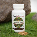 AyuMantra Madhuant supplement bottle on grass with leaves and stones in the background