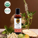 Bottle of Maharanayan Organic Ayurvedic Oil with USDA Organic and OneCert Organic logos, surrounded by natural elements on a wooden surface.