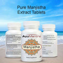 AyuMantra Manjistha Extract Tablets bottles on a beach with blue sky and ocean.