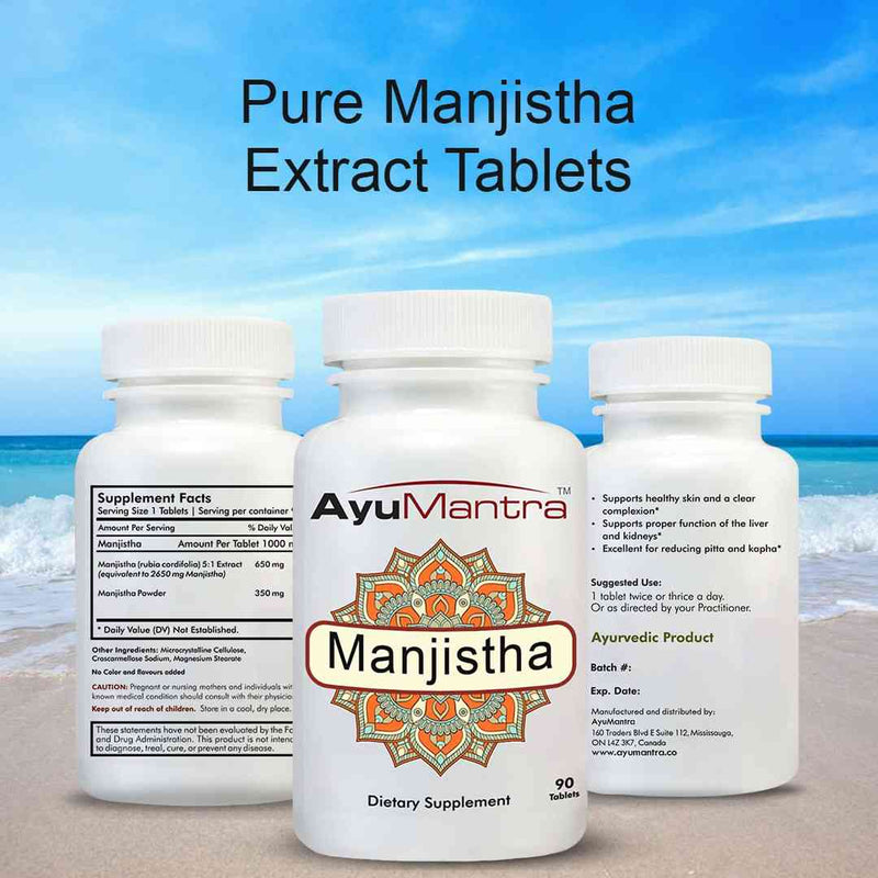 AyuMantra Manjistha Extract Tablets bottles on a beach with blue sky and ocean.