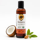 Bottle of Murivenna organic ayurvedic oil with a coconut, almond, and leaves on a white background
