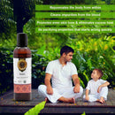 Man and child sitting outdoors with a bottle of Neem oil, surrounded by greenery.