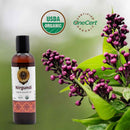 Nirgundi organic apothecary oil bottle with purple flowers and green leaves on a light green background.