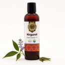 Bottle of Nirgundi organic ayurvedic oil with leaves and flowers on a white background