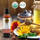 Pinda organic ayurvedic oil bottle with USDA Organic and OneCert Organic logos, honeycomb, flowers, and jars on a wooden surface.