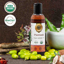 Bottle of Psorivell Organic Ayurvedic Oil with USDA Organic and OneCert Organic logos, surrounded by green leaves and a wooden background.