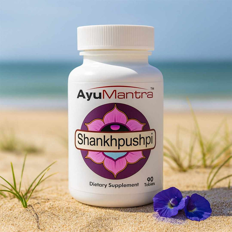 AyuMantra Shankhpushpi dietary supplement bottle on a sandy beach with ocean view