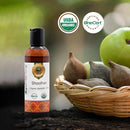 Bottle of AvilVedha Shoolhar organic ayurvedic oil with USDA Organic and OneCert certification logos, surrounded by fruits and a basket.
