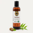 Bottle of Shoolhar Ayurvedic oil with leaves and nuts on a white background