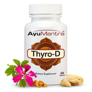 AyuMantra Thyro-D tablets bottle with pink flower and herbs arranged in front on a white background.