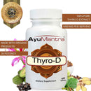 AyuMantra Thyro-D tablets bottle with badge and assorted organic herbs around the base.