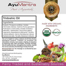 AyuMantra Tridoshic Oil packaging with ingredients list, organic certification logos, and natural elements.