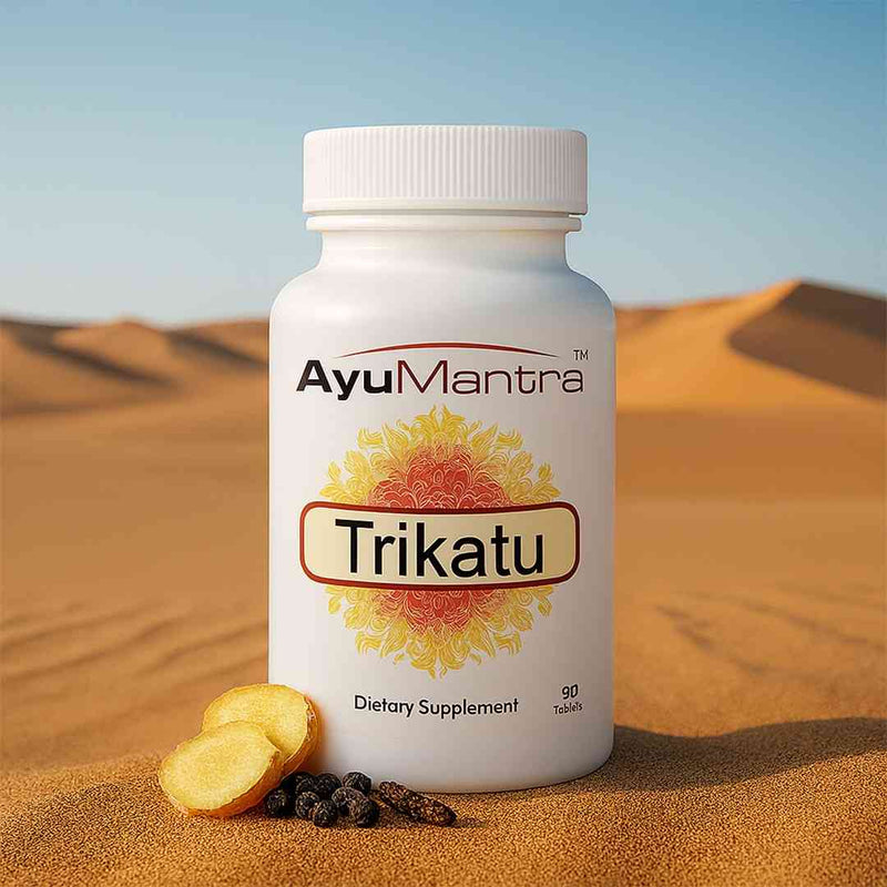 AyuMantra Trikatu tablets bottle on desert sand with ginger slices and black pepper in front.