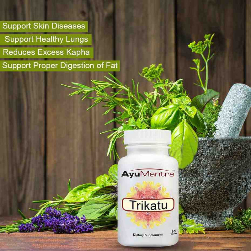 AyuMantra Trikatu tablets bottle beside fresh herbs and mortar, with key health benefits listed.