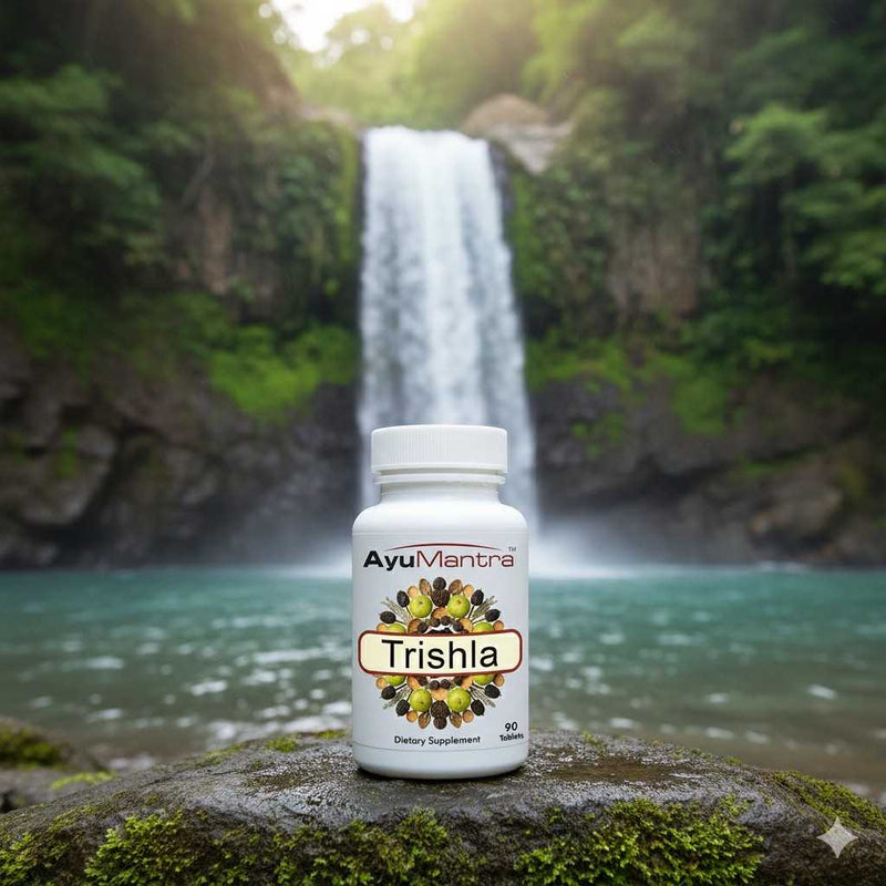 AyuMantra Trishala tablets bottle placed on a rock in front of a waterfall and forest pool.