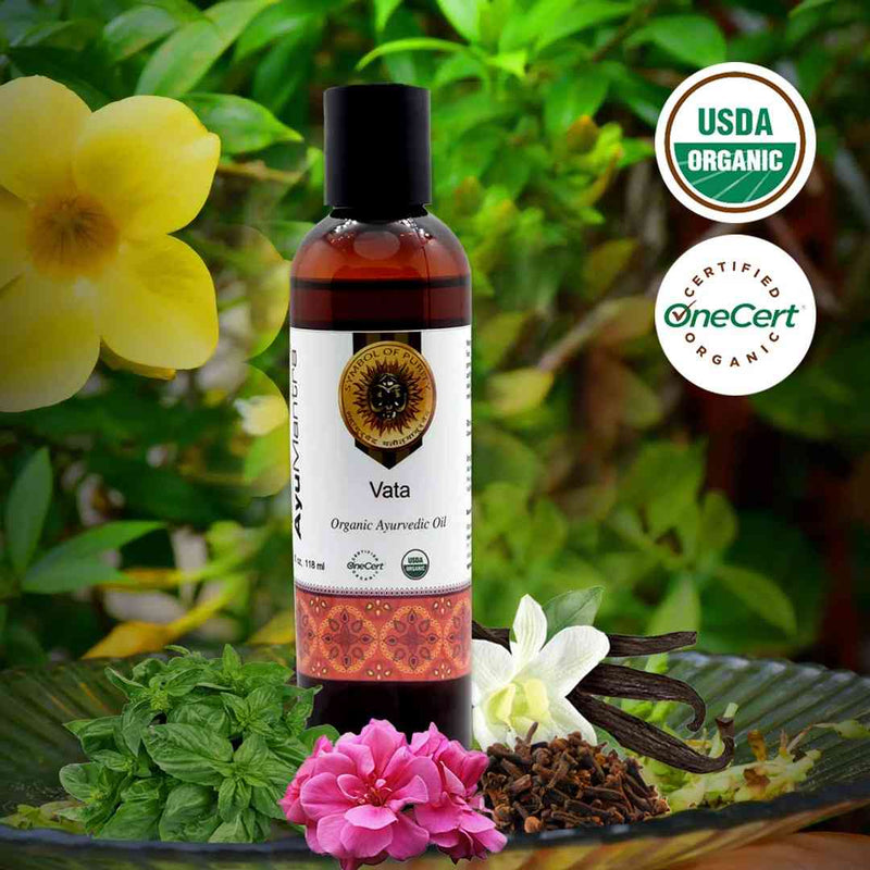 Bottle of Vata Organic Ayurvedic Oil with USDA Organic and OneCert Organic logos, surrounded by flowers and herbs.