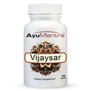 AyuMantra Vijaysar tablets bottle with fresh yellow flower and green leaves on white background.