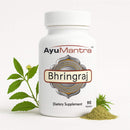 Ayumantra Bhringraj tablets bottle with fresh bhringraj leaves and herbal powder on white background.