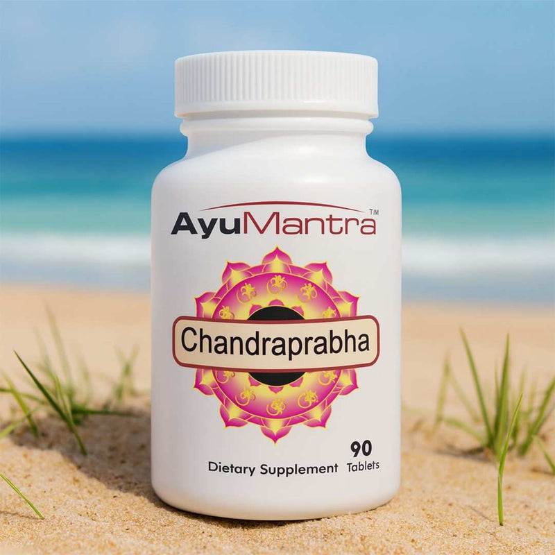 AyuMantra Chandraprabha vati tablets bottle on beach sand with blue sea in the background.